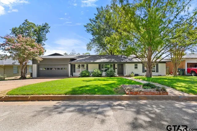 a front view of a house with a garden and trees