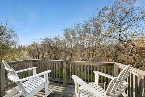 a view of a roof deck with wooden fence and trees