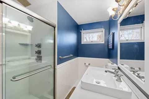 a bathroom with a sink and mirror with bathtub