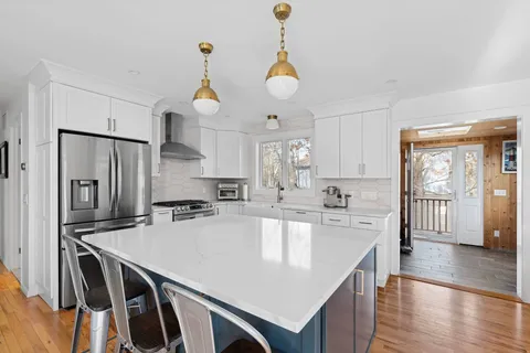 a kitchen with kitchen island a stove a sink a center island and wooden floor