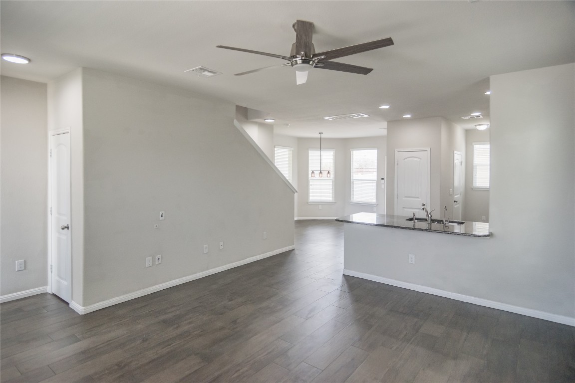 332 Cane River Road Pflugerville, TX 78660 - Photo 10 of 30 an empty room with wooden floor and a kitchen