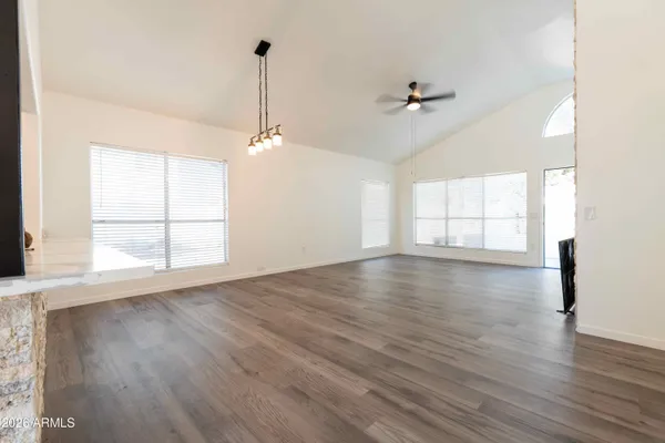 an empty room with wooden floor ceiling fan and windows