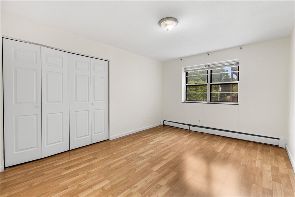 4925 Washington Street, Unit 304 Boston, MA 02132 - Photo 11 of 25 a view of an empty room with wooden floor and a window