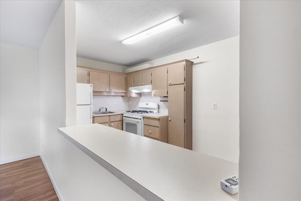 4925 Washington Street, Unit 304 Boston, MA 02132 - Photo 14 of 25 a kitchen with stainless steel appliances a refrigerator and a stove top oven