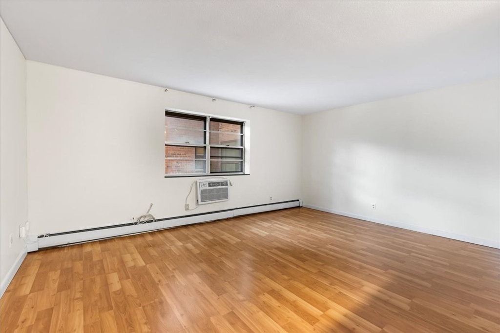 4925 Washington Street, Unit 304 Boston, MA 02132 - Photo 2 of 25 an empty room with wooden floor and windows