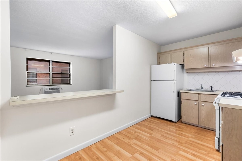4925 Washington Street, Unit 304 Boston, MA 02132 - Photo 7 of 25 a kitchen with a refrigerator and a sink