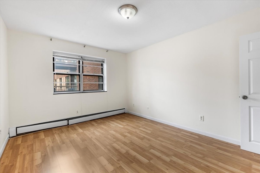 4925 Washington Street, Unit 304 Boston, MA 02132 - Photo 10 of 25 an empty room with wooden floor and windows