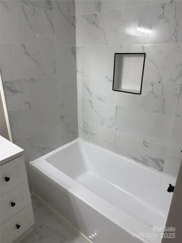 a white bath tub sitting next to a white sink and vanity
