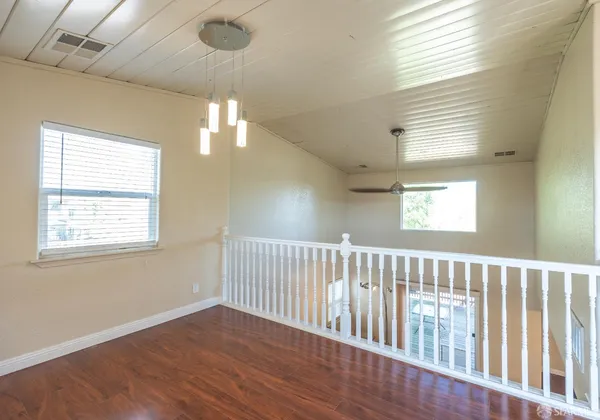 a view of an empty room with wooden floor and windows