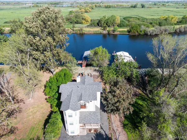 an aerial view of a house with a garden and lake view
