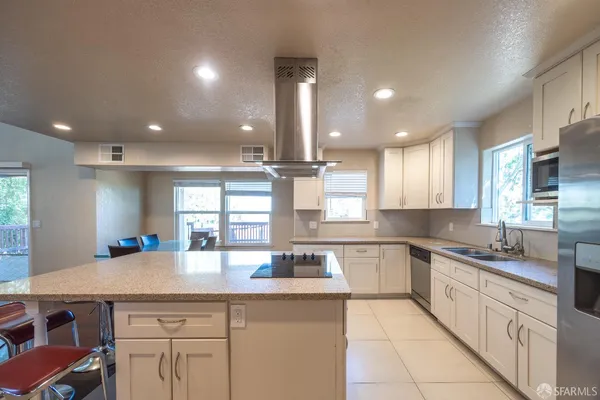 a kitchen with kitchen island granite countertop a sink counter top space appliances and cabinets