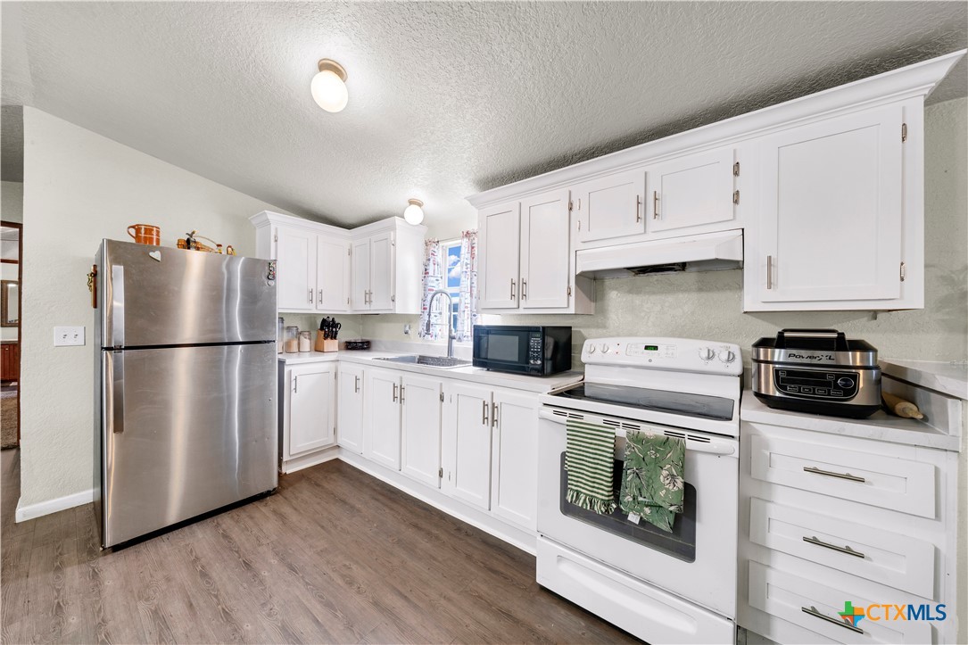 11791 Kinney Road Atascosa, TX 78002 - Photo 13 of 20 a kitchen with cabinets stainless steel appliances and wooden floor