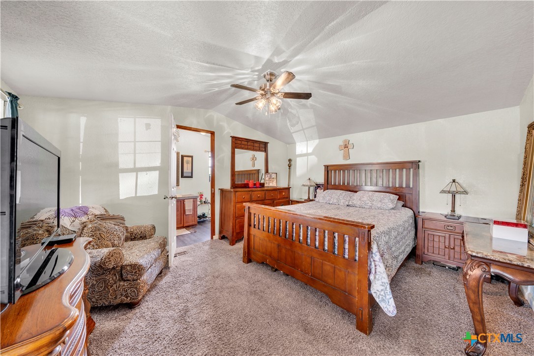 11791 Kinney Road Atascosa, TX 78002 - Photo 16 of 20 a bedroom with a bed and a chandelier