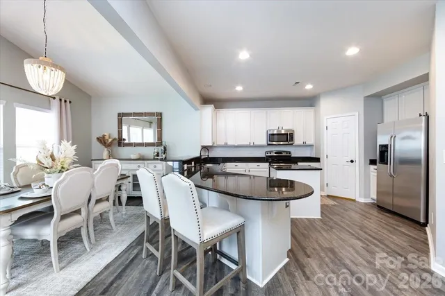 a kitchen with stainless steel appliances a dining table chairs stove and refrigerator