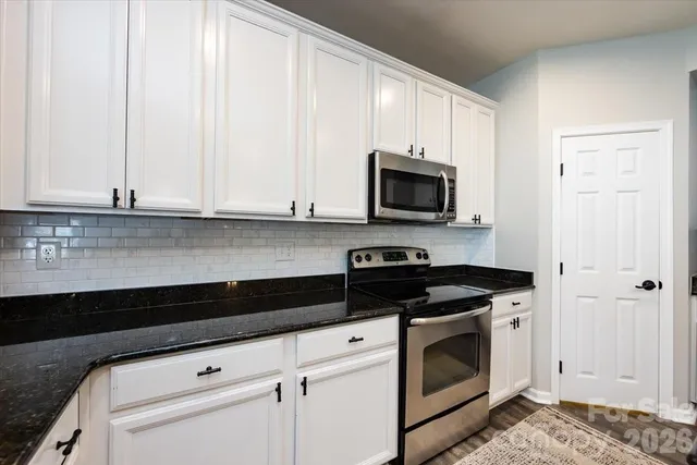 a kitchen with granite countertop white cabinets and black appliances