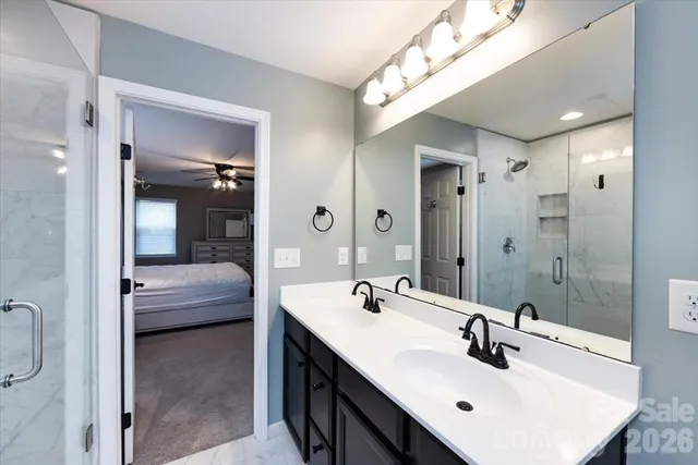 a en suite bathroom with a double vanity sink a mirror and shower