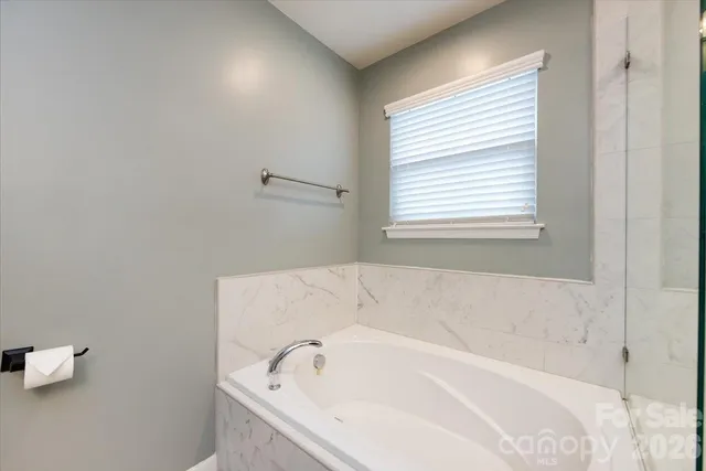 a white bath tub sitting in a bathroom next to a window