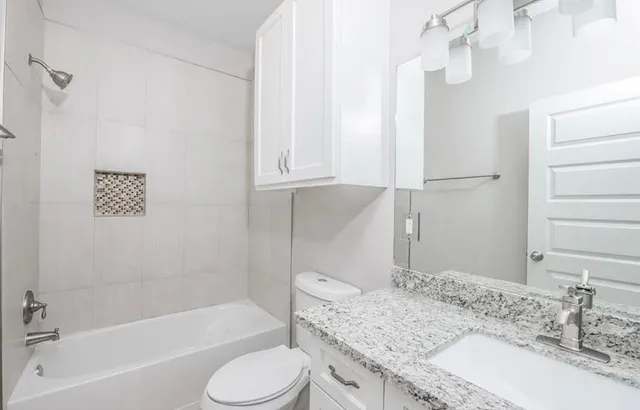 a bathroom with a granite countertop sink toilet and shower
