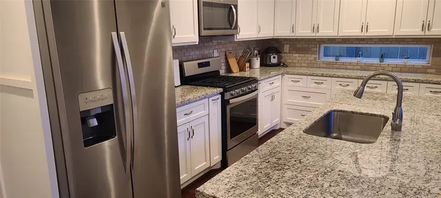 a kitchen with stainless steel appliances granite countertop a stove a refrigerator and a sink