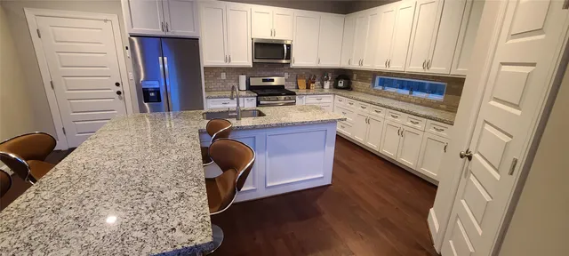 a kitchen with stainless steel appliances granite countertop a stove refrigerator sink and microwave