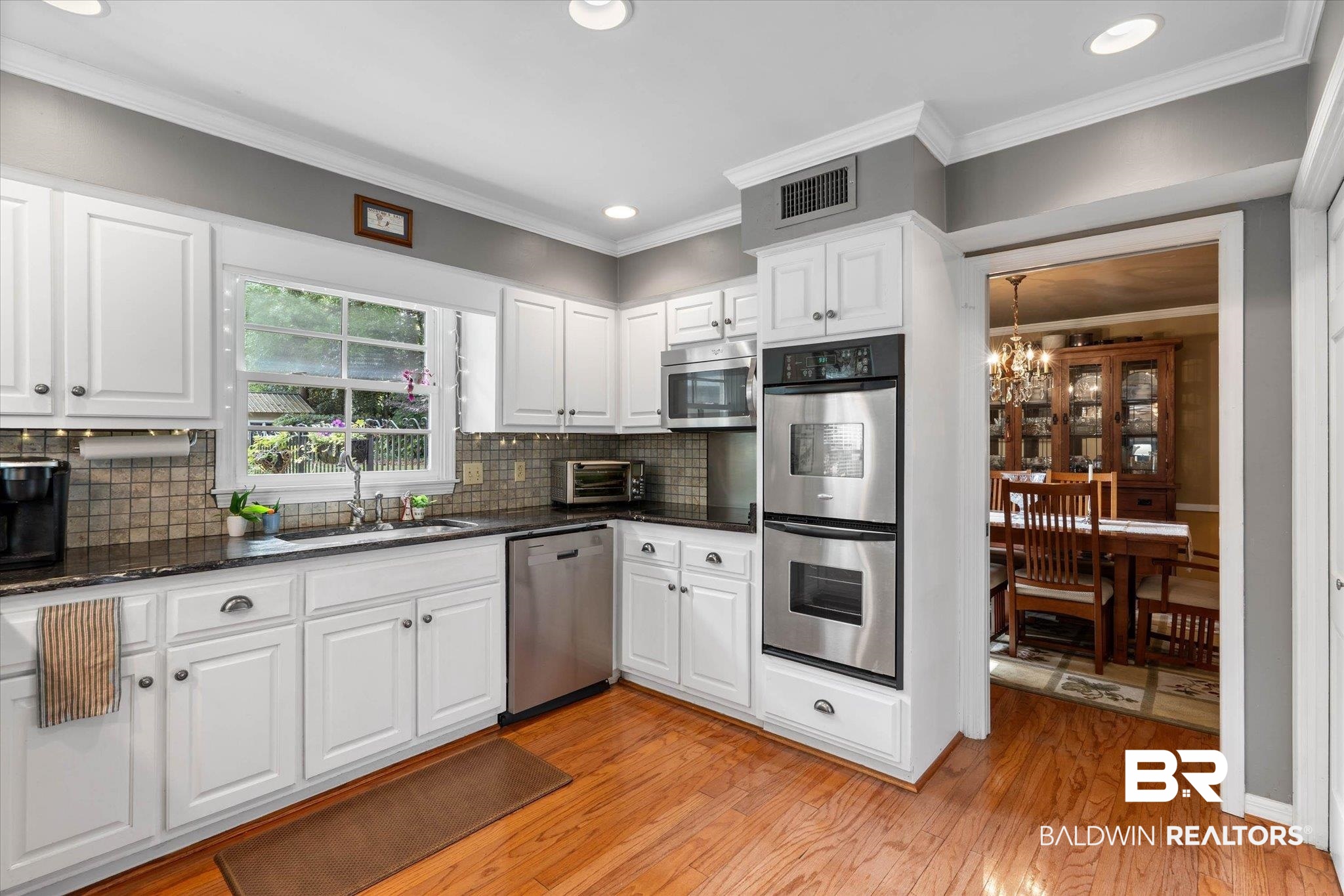 559 East Cumberland Road Mobile, AL 36608 - Photo 16 of 48 Kitchen with white cabinetry, stainless steel appliances, crown molding, light wood-type flooring, and dark stone countertops