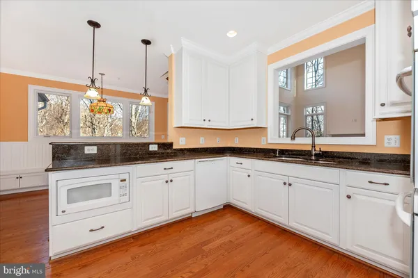 a large white kitchen with wooden floor and stainless steel appliances