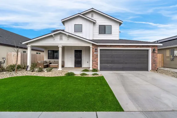 a view of a white house with a yard potted plants and a table and chair