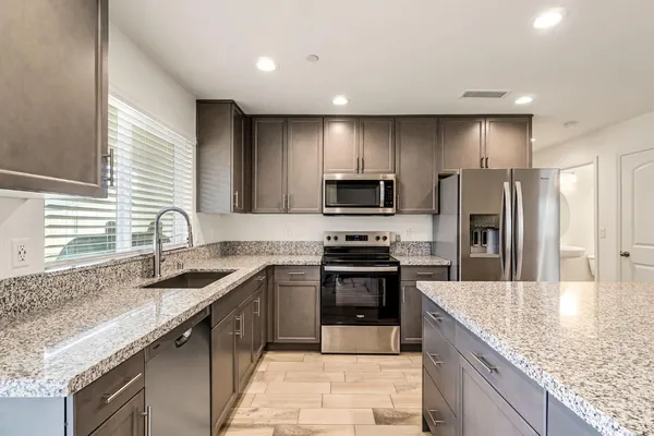 a kitchen with stainless steel appliances granite countertop a sink stove microwave refrigerator and cabinets