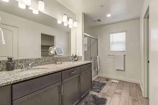 a bathroom with a granite countertop sink a large mirror a and a shower