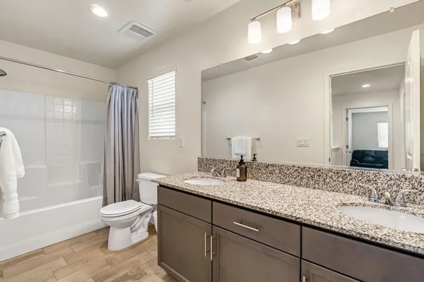 a bathroom with a granite countertop sink a toilet a mirror and shower
