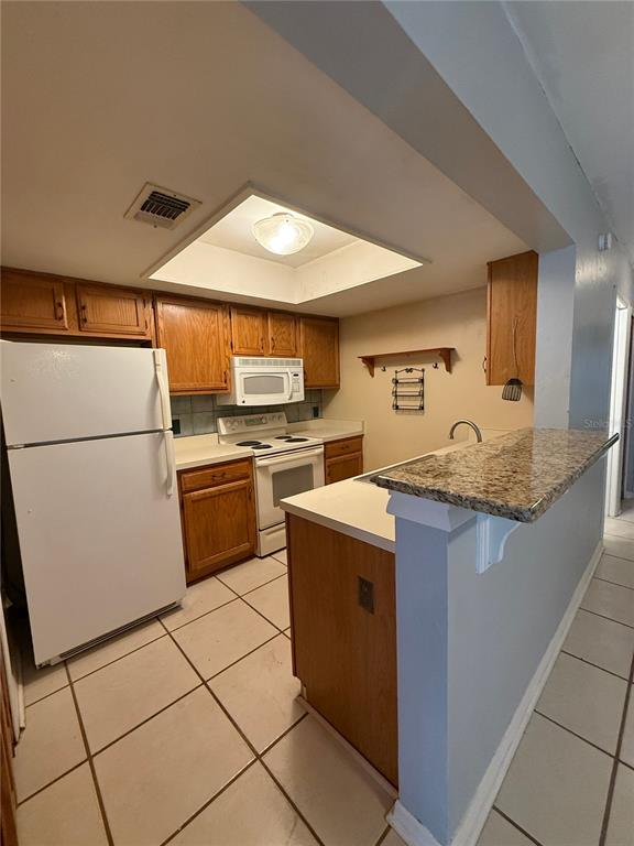 7200 Southwest 8th Avenue, Unit T128 Gainesville, FL 32607 - Photo 10 of 38 a kitchen with granite countertop a sink a stove and a refrigerator
