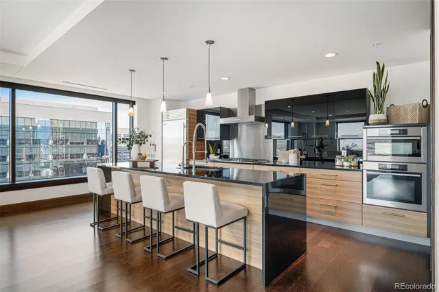 a kitchen with stainless steel appliances granite countertop a stove top oven a sink a dining table and chairs with wooden floor