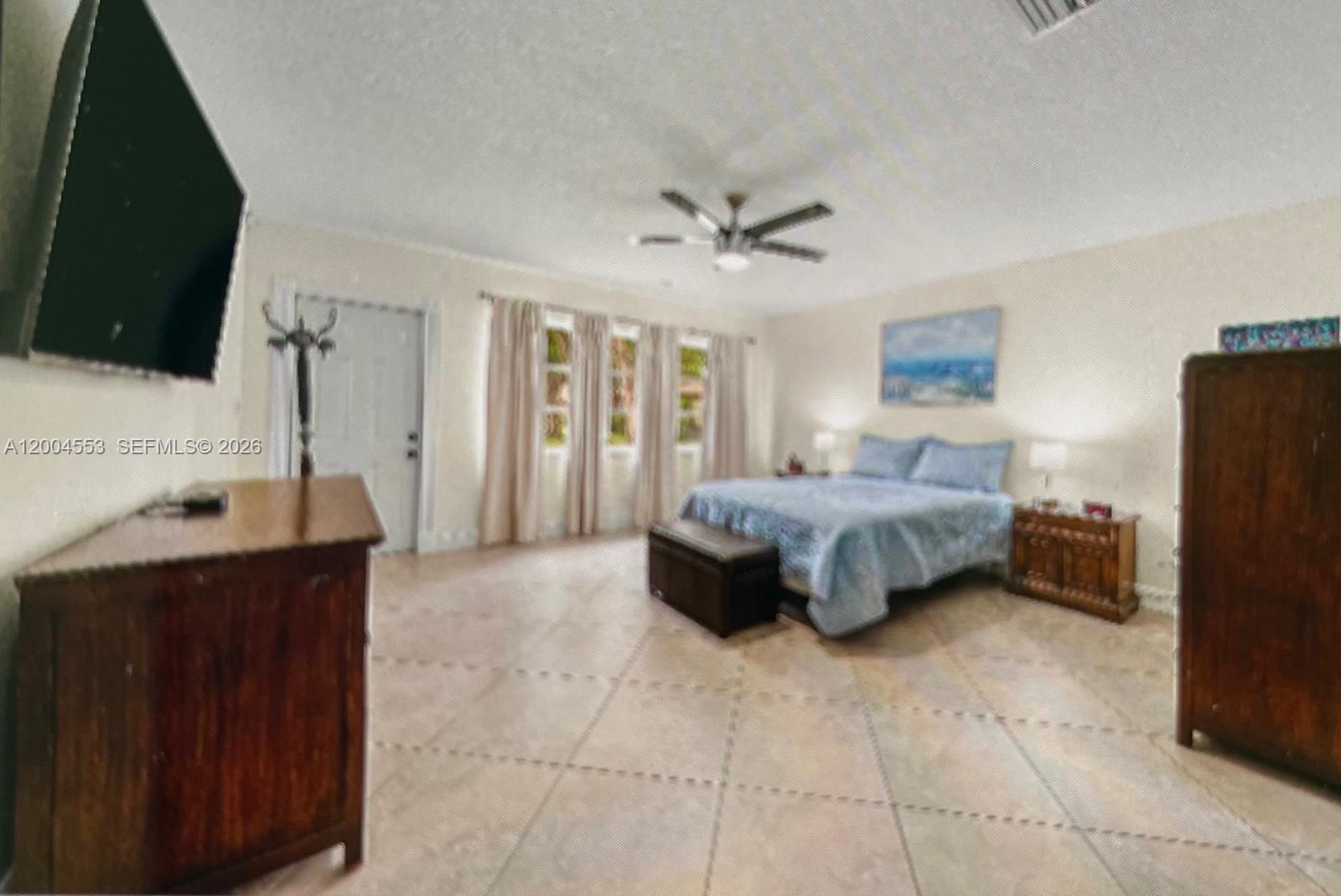 13990 Nesting Way, Unit C Delray Beach, FL 33484 - Photo 12 of 18 a spacious bedroom with a bed and a flat screen tv
