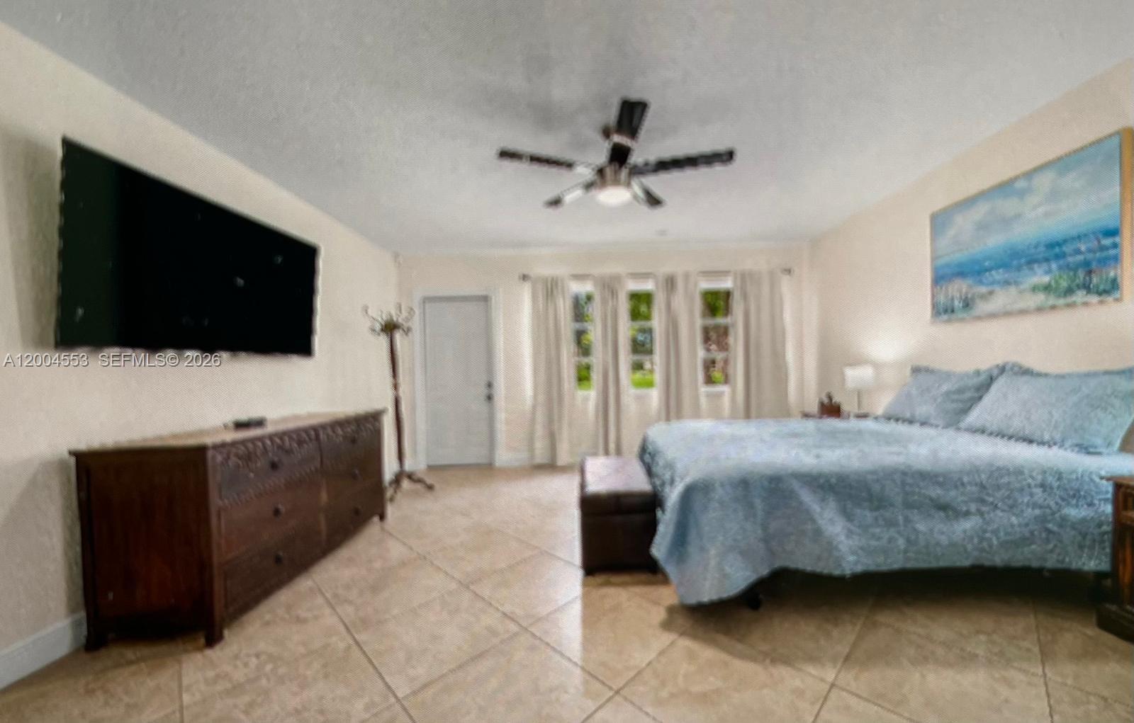 13990 Nesting Way, Unit C Delray Beach, FL 33484 - Photo 13 of 18 a spacious bedroom with a bed and a flat screen television