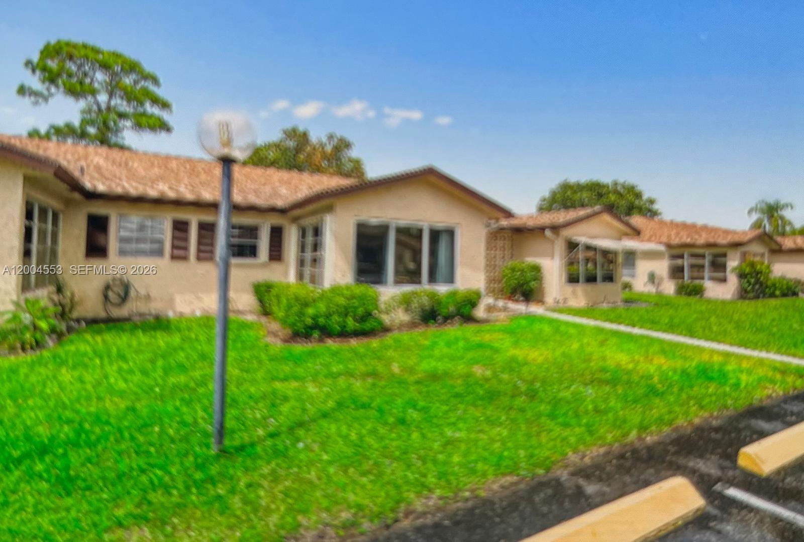 13990 Nesting Way, Unit C Delray Beach, FL 33484 - Photo 2 of 18 a front view of a house with a garden and plants