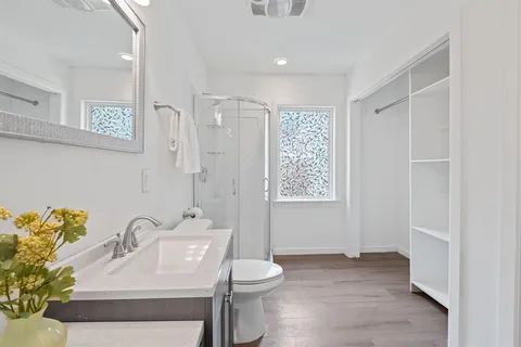 a bathroom with a toilet a sink a mirror a window and vanity