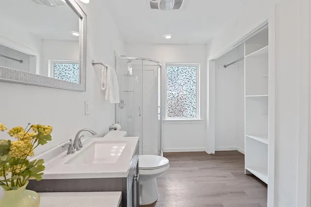 a bathroom with a toilet a sink a mirror a window and vanity