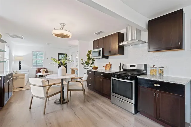 a kitchen with stainless steel appliances granite countertop a refrigerator a stove a sink dishwasher and microwave with wooden floor