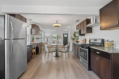 a kitchen with stainless steel appliances a sink dishwasher a stove and a microwave oven with cabinets