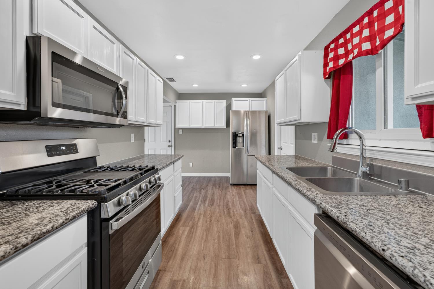 3708 Merrily Way Sacramento, CA 95821 - Photo 8 of 51 Kitchen featuring white cabinetry, wood-finish flooring, stainless steel appliances, granite countertops, and recessed lighting