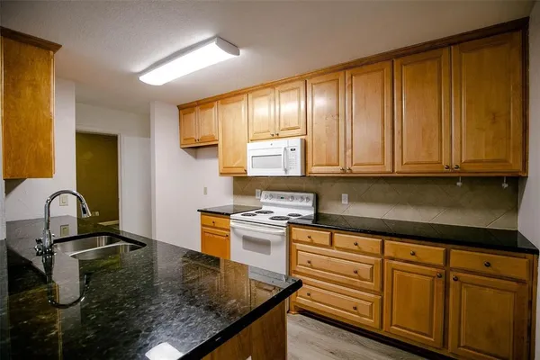 a kitchen with kitchen island granite countertop a sink stove and cabinets
