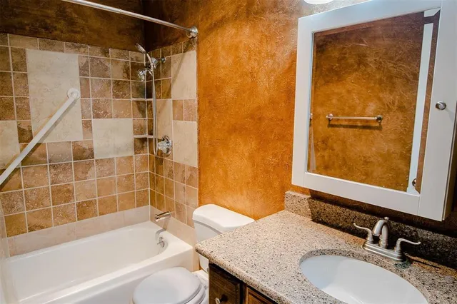 a bathroom with a granite countertop sink toilet and shower