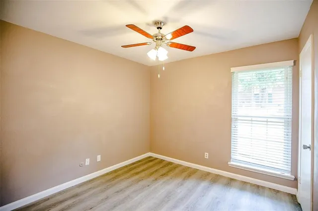 an empty room with a window and a ceiling fan