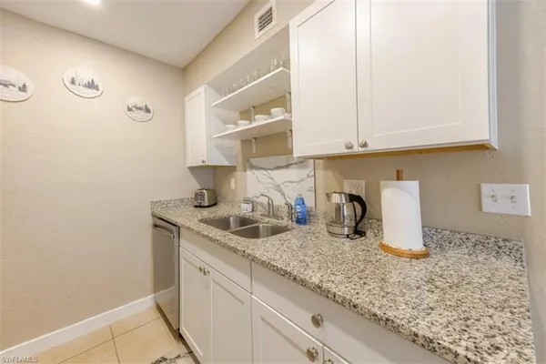 a kitchen with granite countertop a sink a stove and cabinets