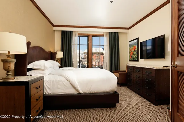 a bedroom with a bed and a flat tv screen on wall