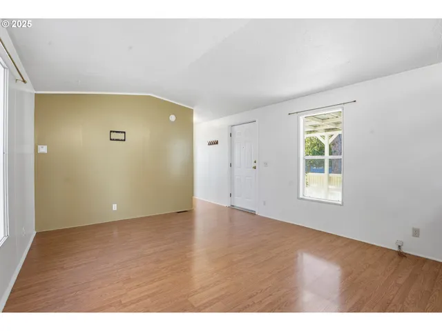 a view of an empty room with window and wooden floor