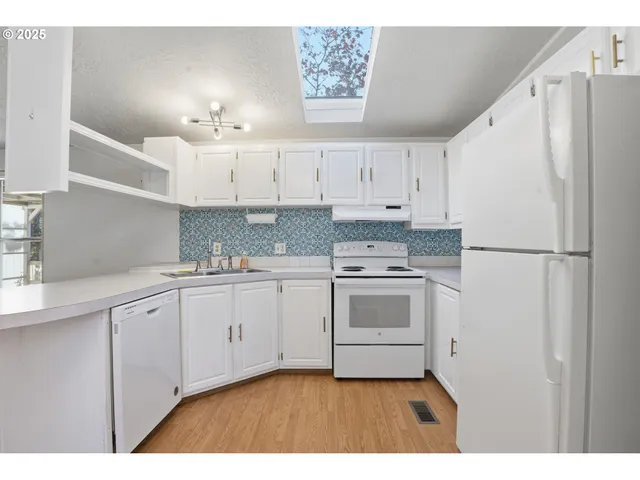 a kitchen with granite countertop white cabinets and white appliances