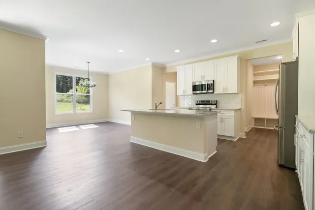 a kitchen with stainless steel appliances granite countertop a refrigerator a stove top oven a sink dishwasher and wooden floor