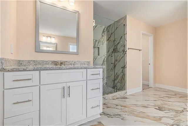a bathroom with a granite countertop sink a mirror a vanity and a shower