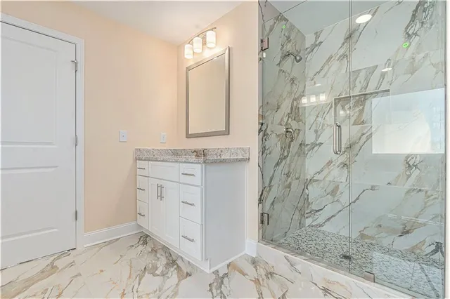 a bathroom with a granite countertop shower a sink and a mirror